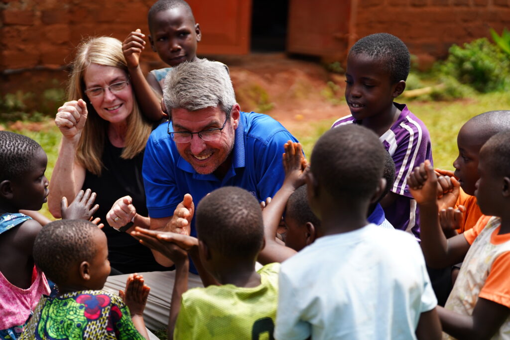 Show Mercy International Founders playing rock paper scissors with children.