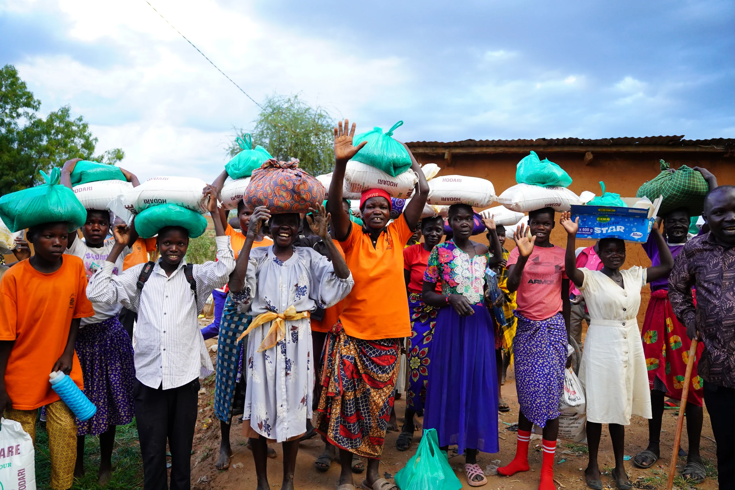 Community members carrying bags of food after a food distribution in Uganda.