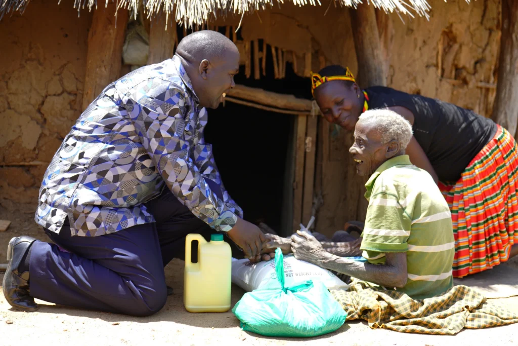 Show Mercy team member delivering food and supplies to an elderly man at his home in Uganda.